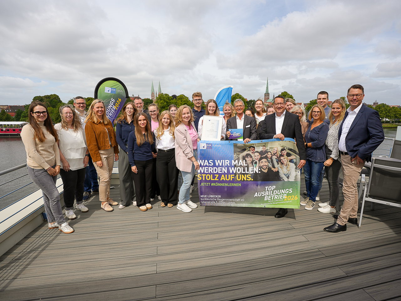 Team der Neuen Lübecker Norddeutschen Baugenossenschaft mit Urkunde auf einer Terrasse