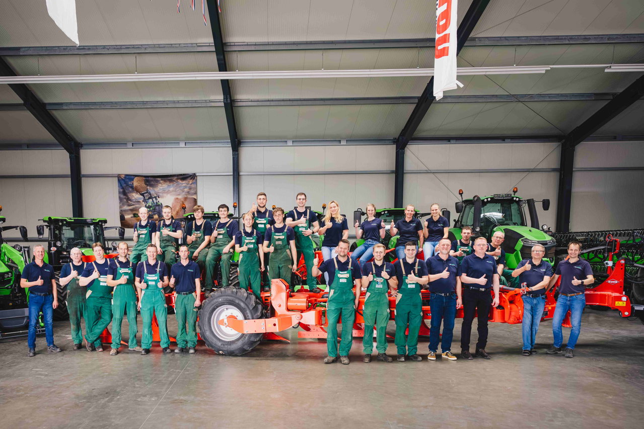 Belegschaft der Roden Landtechnik in der Werkstatthalle zwischen Traktoren
