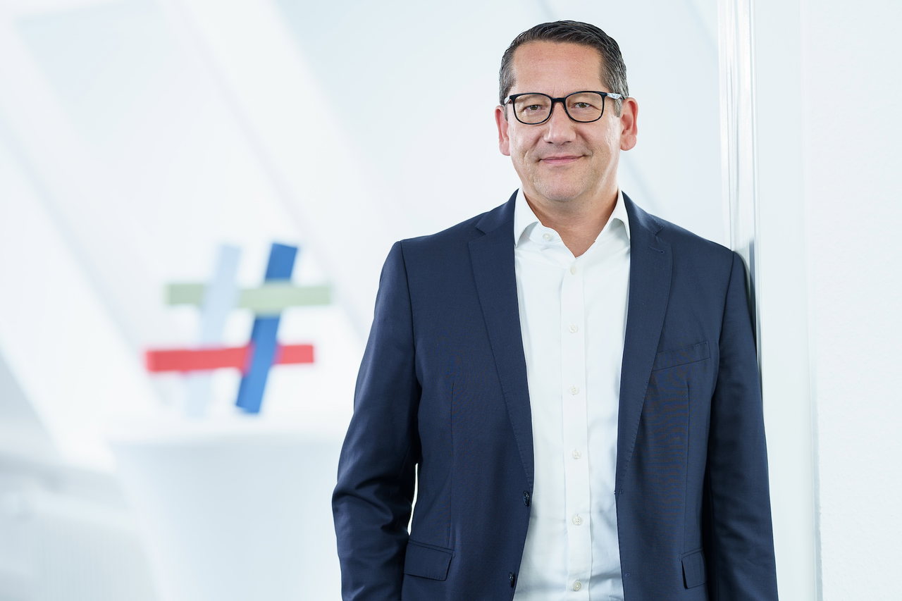 Lars Schöning, Hauptgeschäftsführer der IHK zu Lübeck, im dunklen Anzug vor einer hellen Bürowand