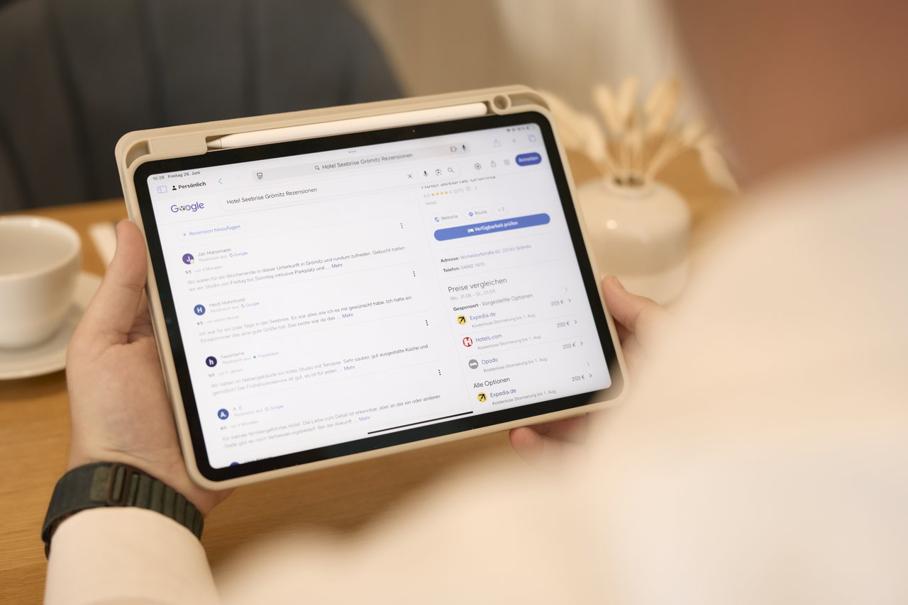 Hände halten ein Tablet, auf dem Google-Bewertungen geöffnet sind