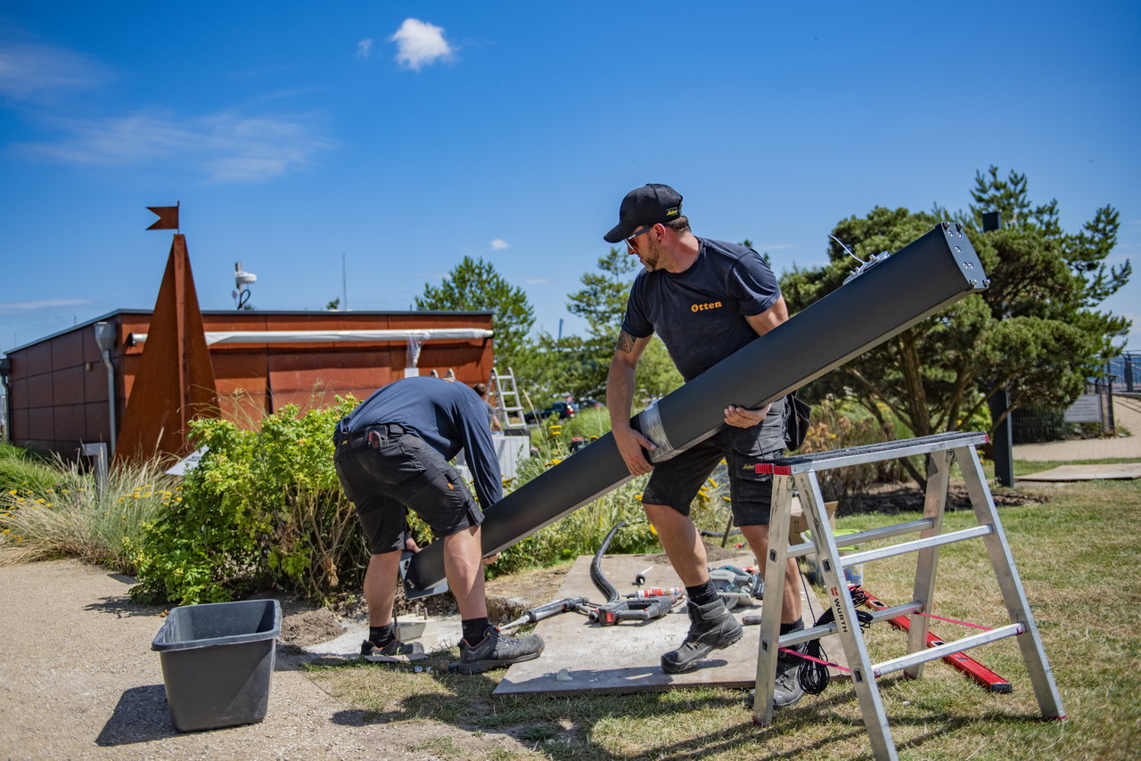Monteure bauen im Freien eine Sonnensegel-Konstruktion auf