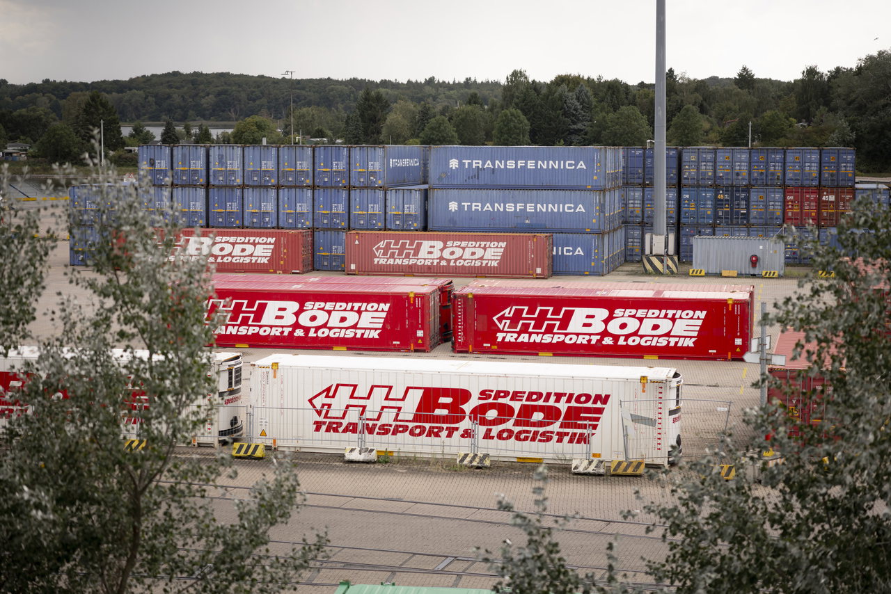 Rote Trailer der Spedition Bode und gestapelte Container auf einem Terminalgelände