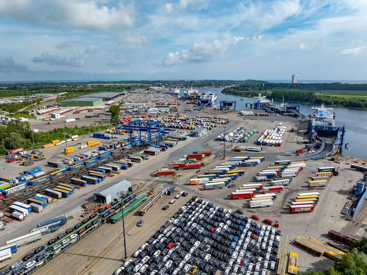 Luftaufnahme des Skandinavienkais in Lübeck-Travemünde mit Fährschiffen, Lkw-Trailern, Neuwagen und Gleisanlagen an der Trave