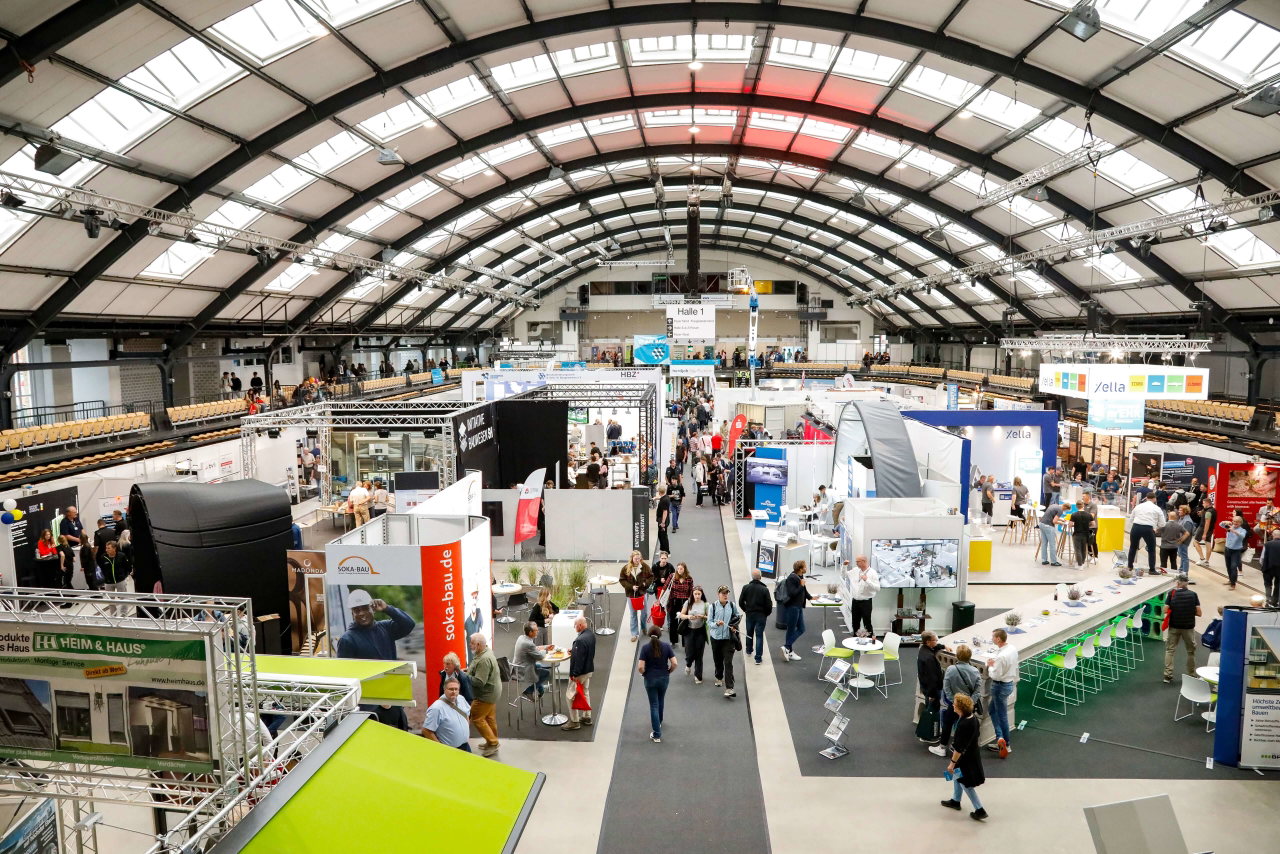 Blick in eine Messehalle mit Ausstellungsständen und Besuchern