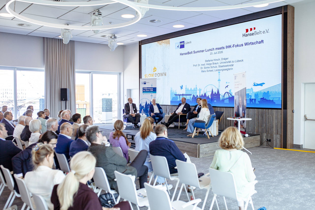 Publikum im Saal vor der Bühne mit der Leinwand „HanseBelt Summer Lunch meets IHK-Fokus Wirtschaft“