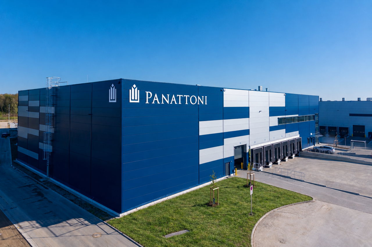 Logistikhalle mit blau-weißer Fassade und Panattoni-Schriftzug vor wolkenlosem blauem Himmel