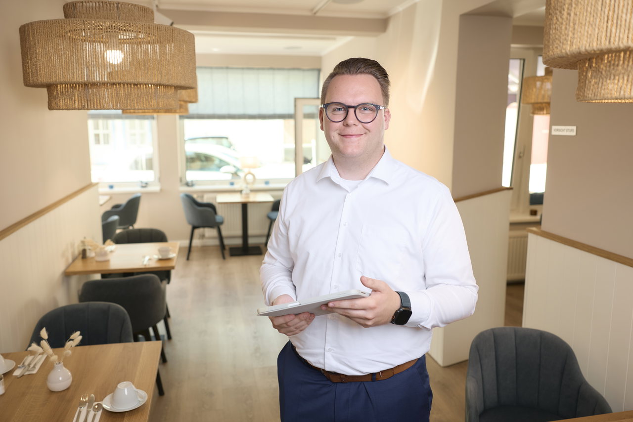 Hotelier mit Tablet im Gastraum seines Hauses