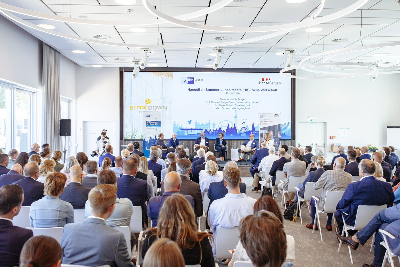 Vollbesetzter Saal mit Blick auf das Podium und die Leinwand