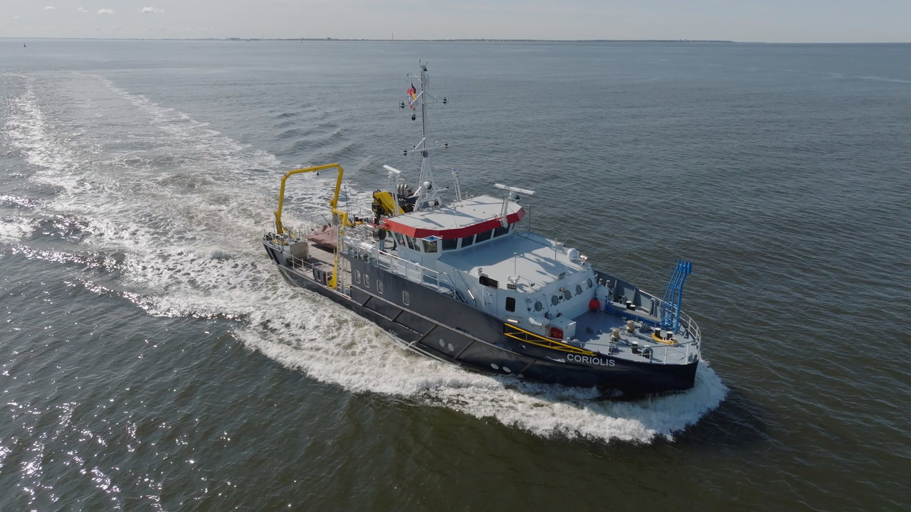 Forschungsschiff Coriolis fährt mit weißer Bugwelle über die Nordsee, Luftaufnahme