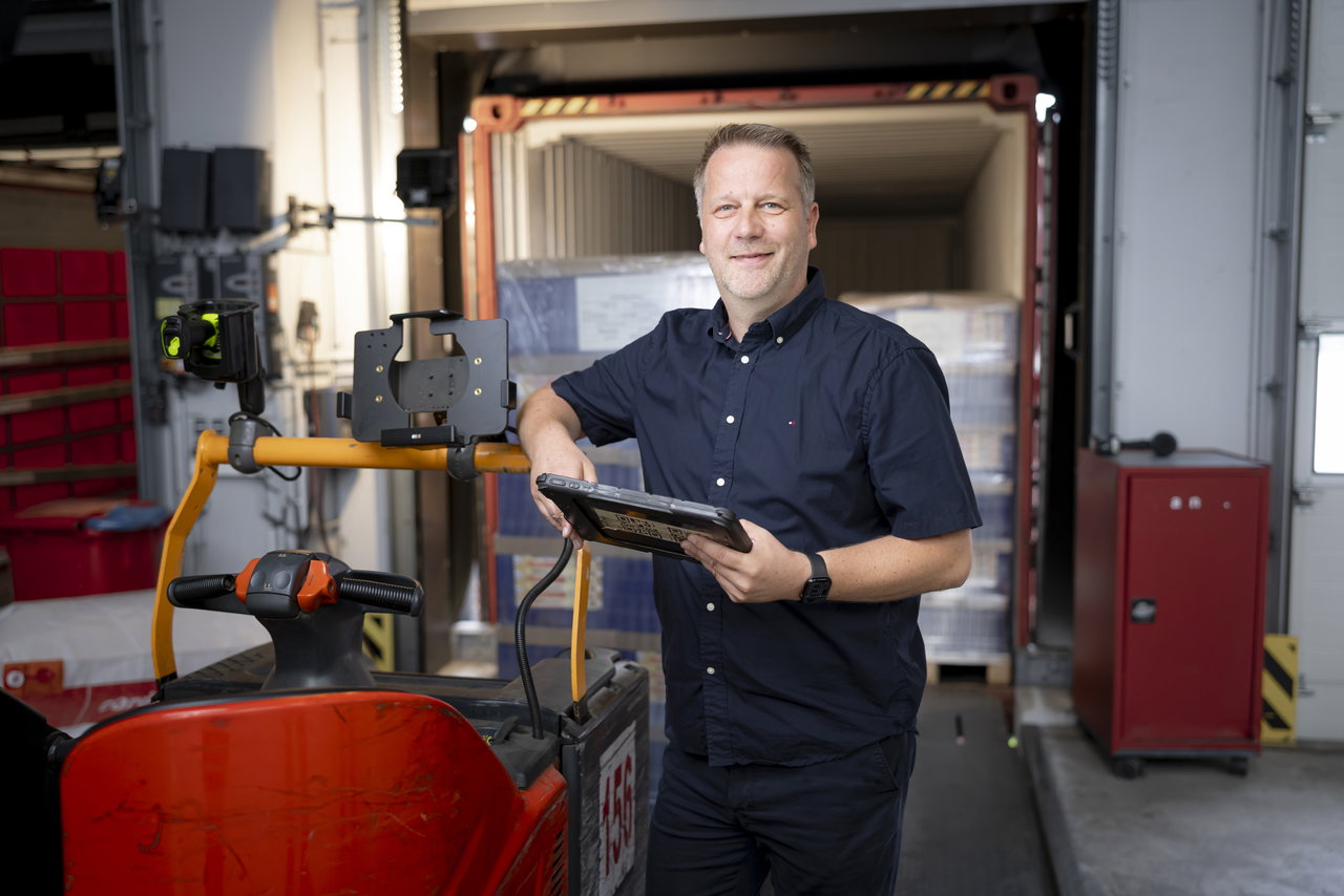 Stev Etzrodt mit Tablet an der Laderampe, hinter ihm ein beladener Container