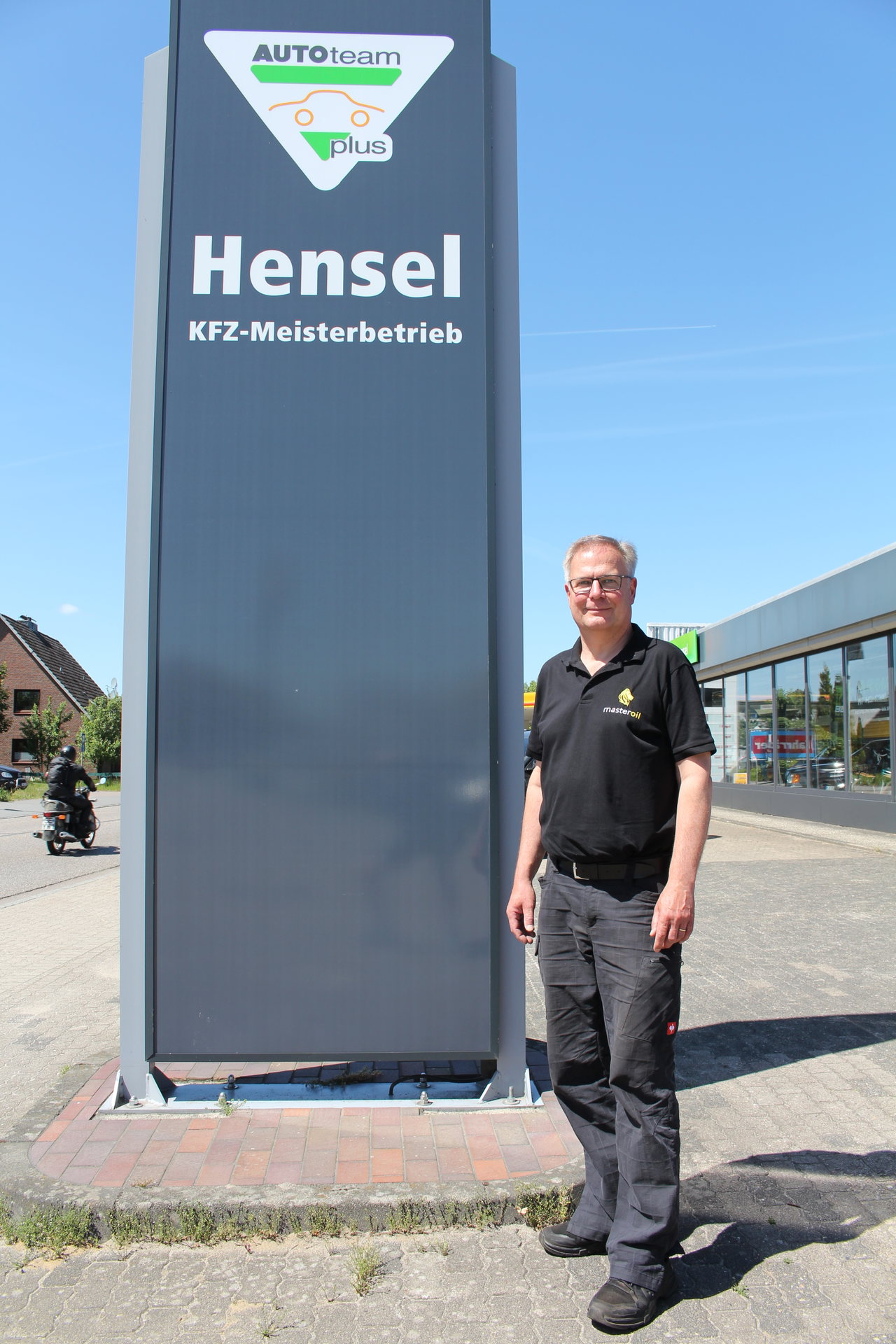 Inhaber des KFZ-Meisterbetriebs Hensel vor der Preisstele seines Autohauses