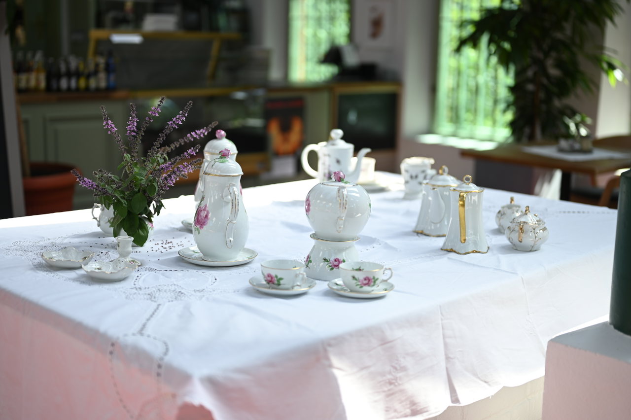 Gedeckter Kaffeetisch mit weißem Porzellan und Blumenstrauß
