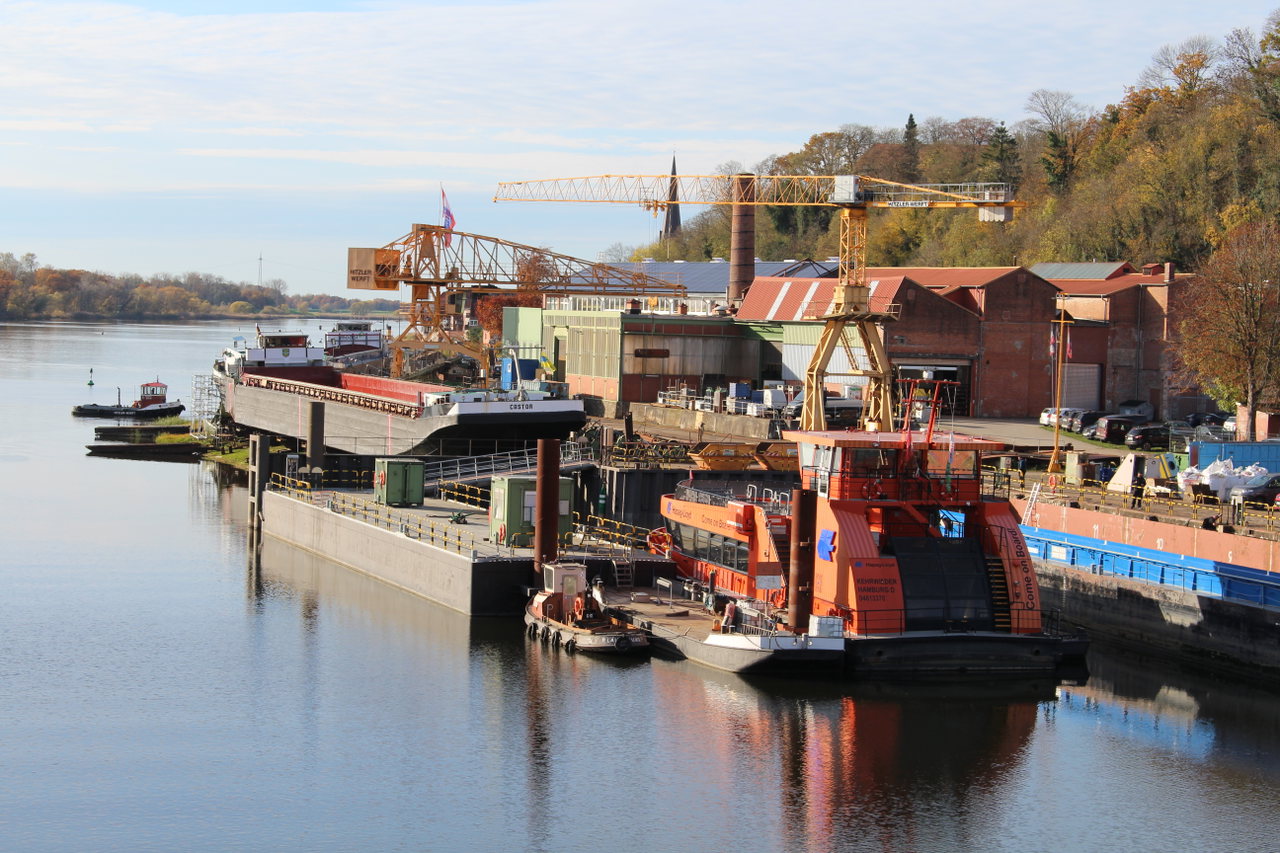 Hitzler Werft in Lauenburg an der Elbe mit Kränen, Backsteinhallen und einem orangefarbenen Schiff am Kai