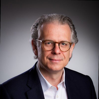 Porträt von Philipp Kroepels mit Brille vor grauem Hintergrund