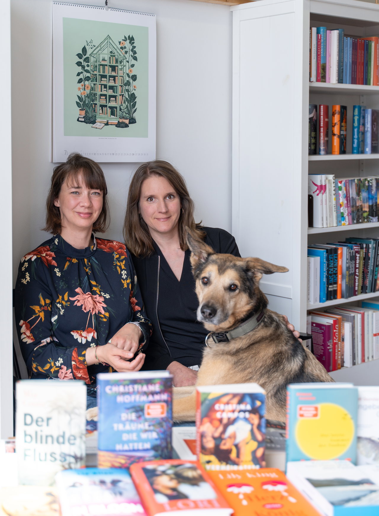 Die beiden Inhaberinnen der Buchhandlung Buchfink mit ihrem Hund zwischen den Bücherregalen
