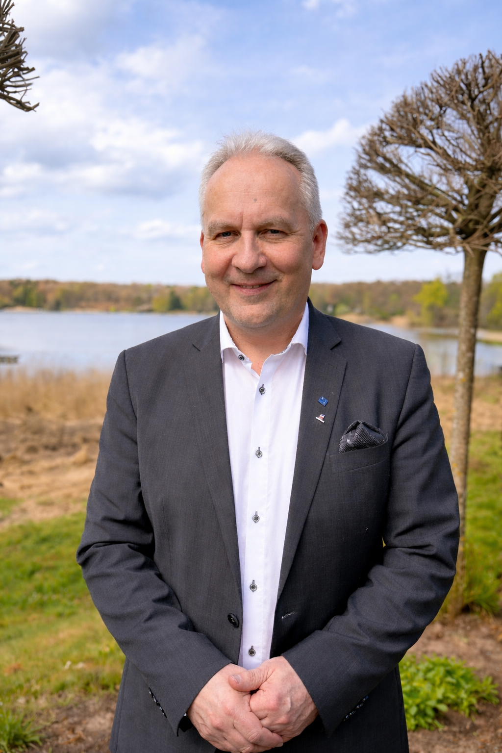 Lutz Frank, Präsident des Dehoga Landesverbands Schleswig-Holstein, im Anzug vor einer Uferlandschaft