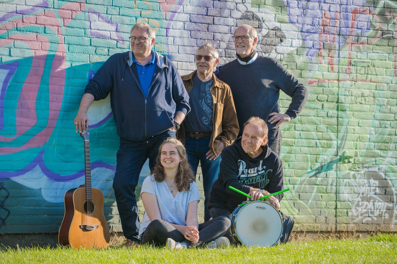 Eine Band mit Gitarre vor einer bunten Wand