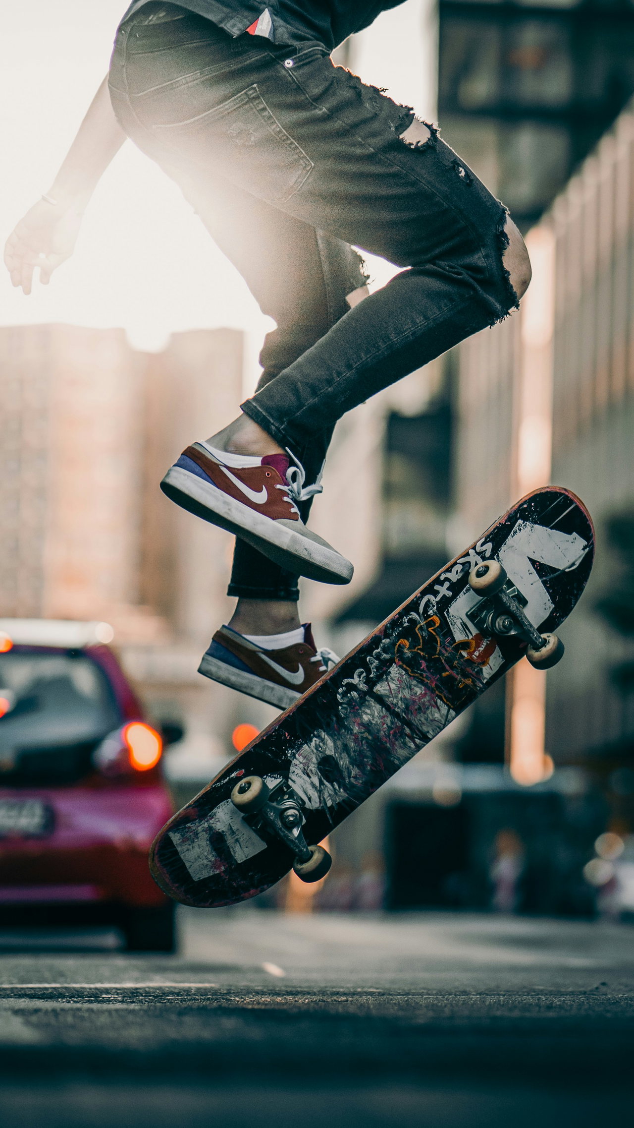 Ein Skater springt auf einer Straße, das Board dreht sich unter seinen Füßen
