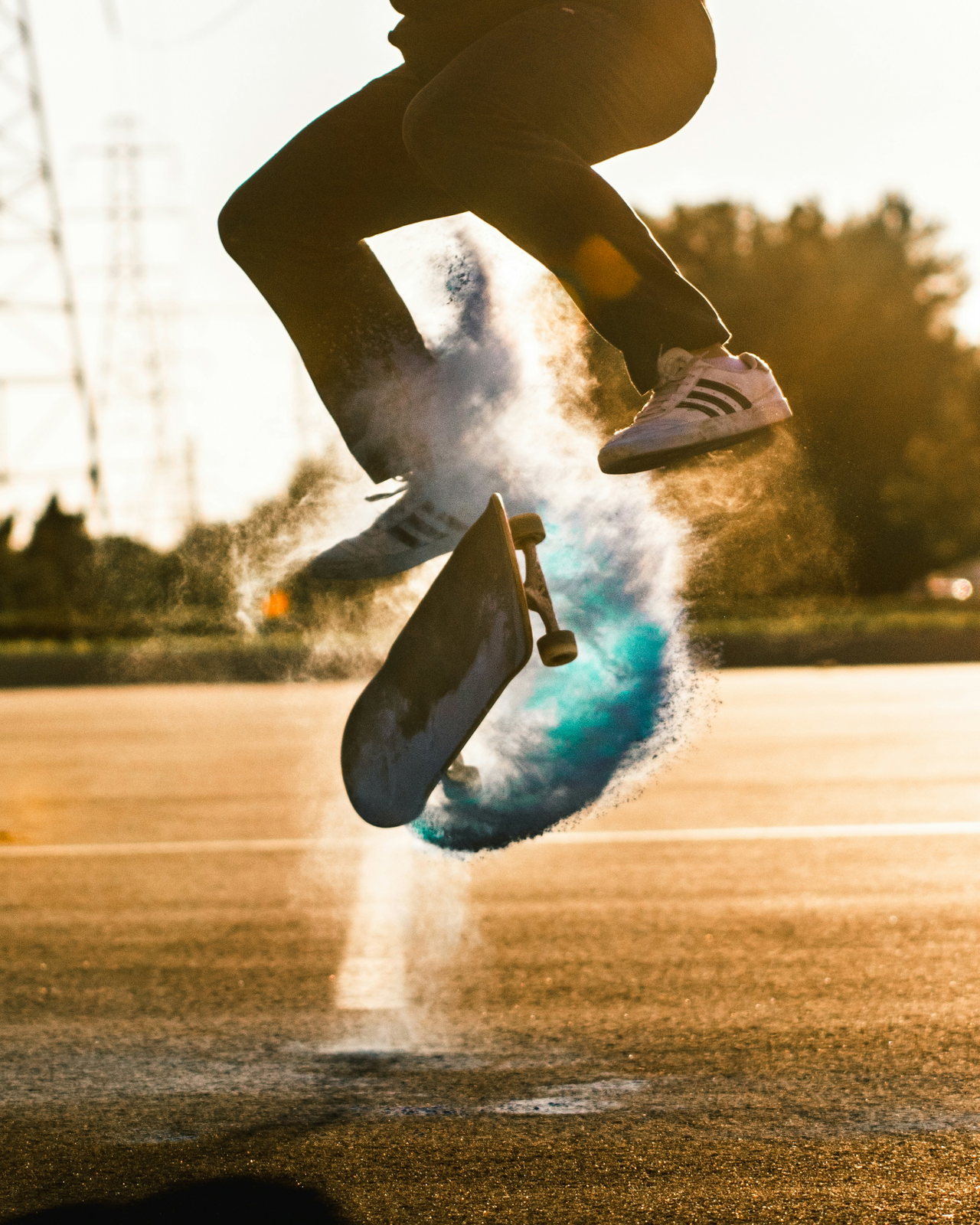 Beine eines Skaters beim Sprung, unter dem Board wirbelt türkisfarbener Staub