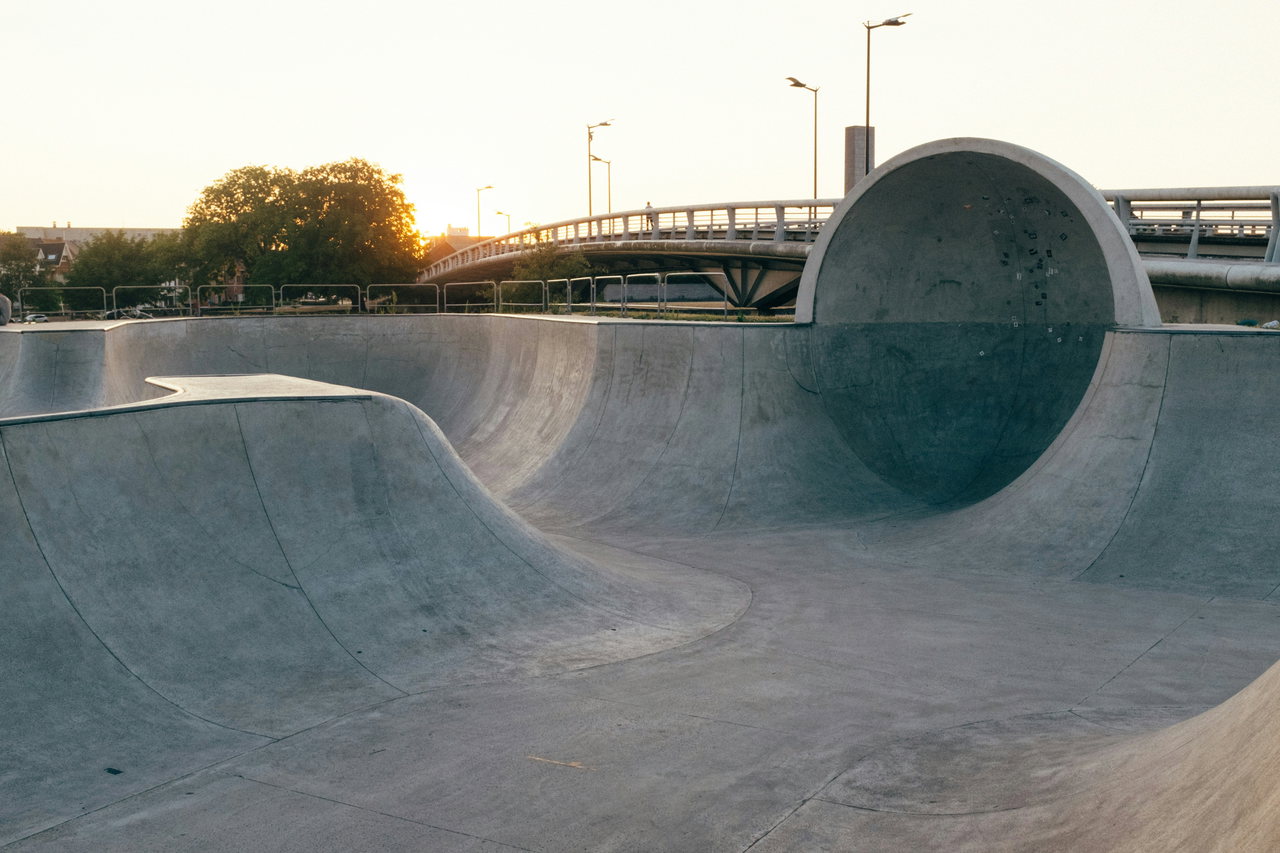 Leerer Skatepark aus Beton mit einer großen runden Röhre im Abendlicht