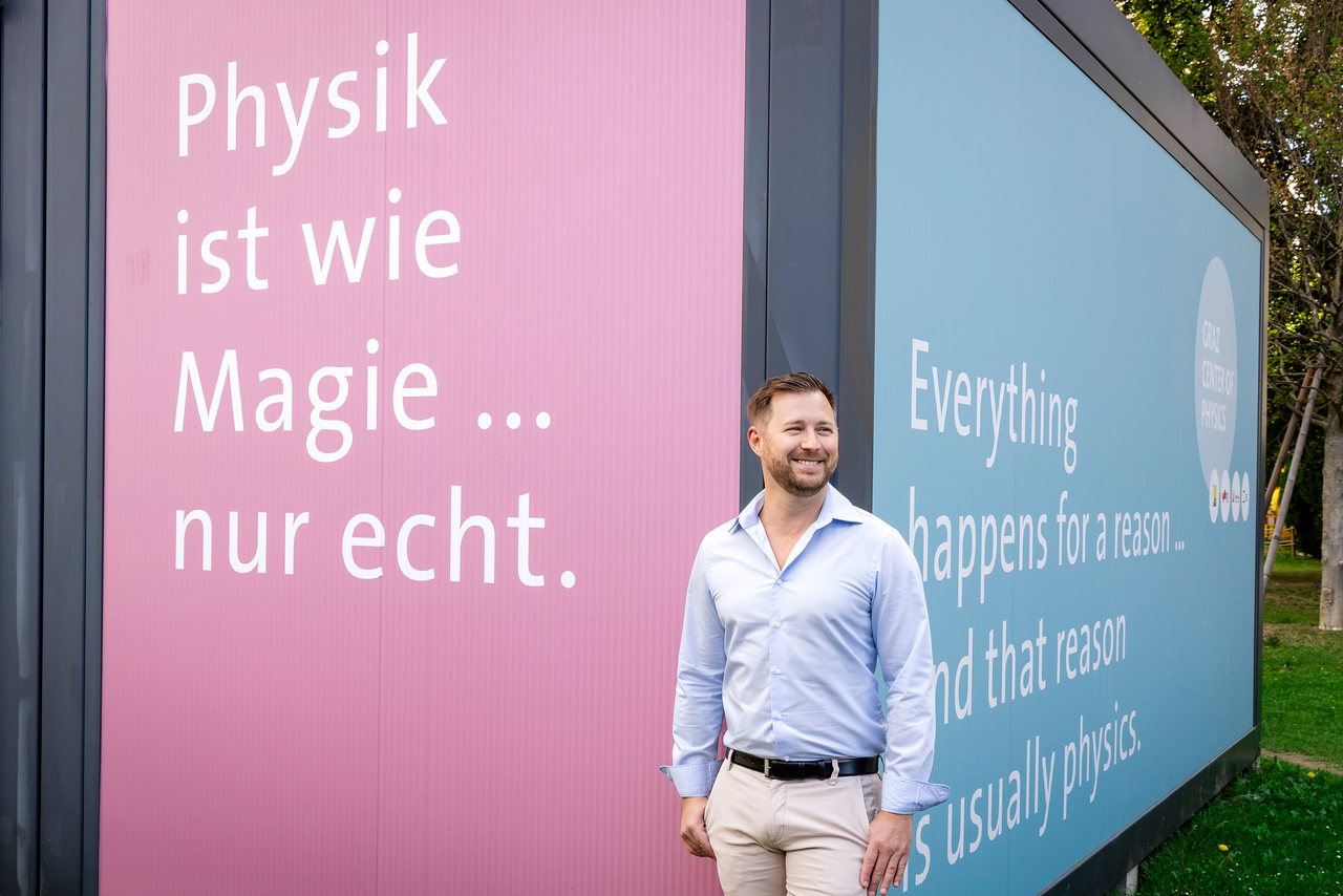 Physiker Jan Enenkel vor einem Container, auf dem Sprüche über Physik zu lesen sind