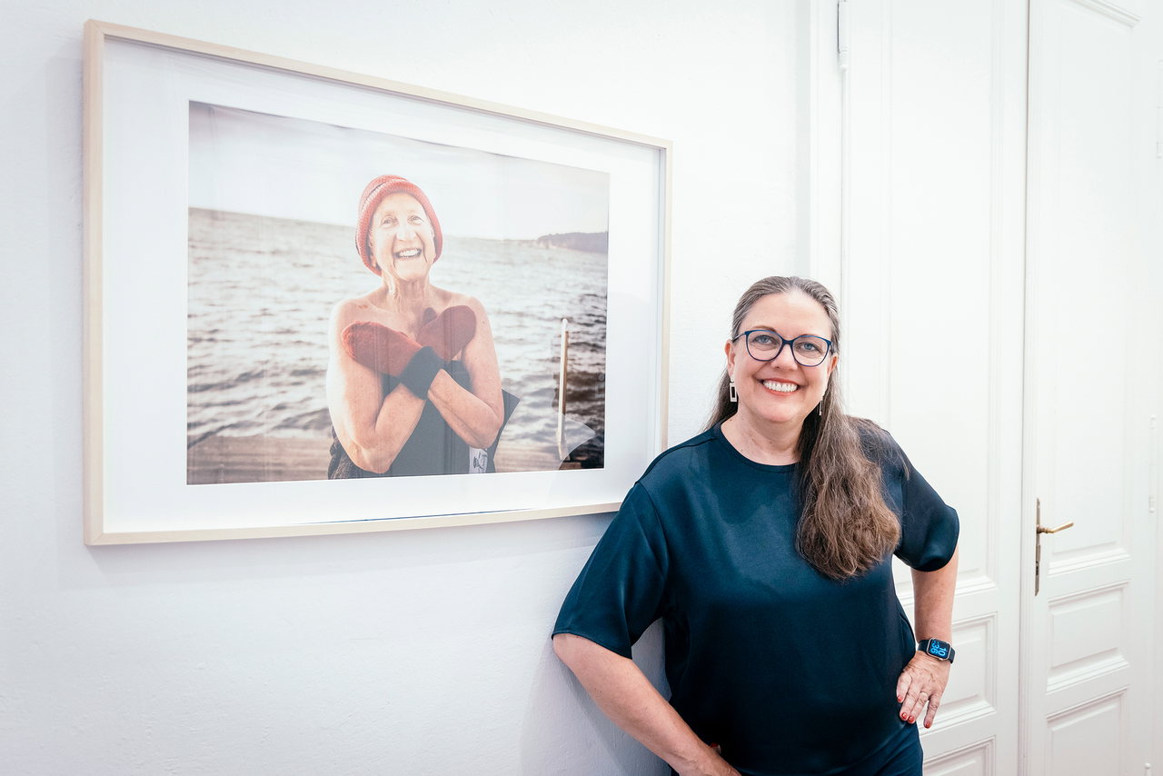 Kulturwissenschaftlerin Ulla Kriebernegg vor dem Foto einer vitalen Seniorin nach dem Eisschwimmen