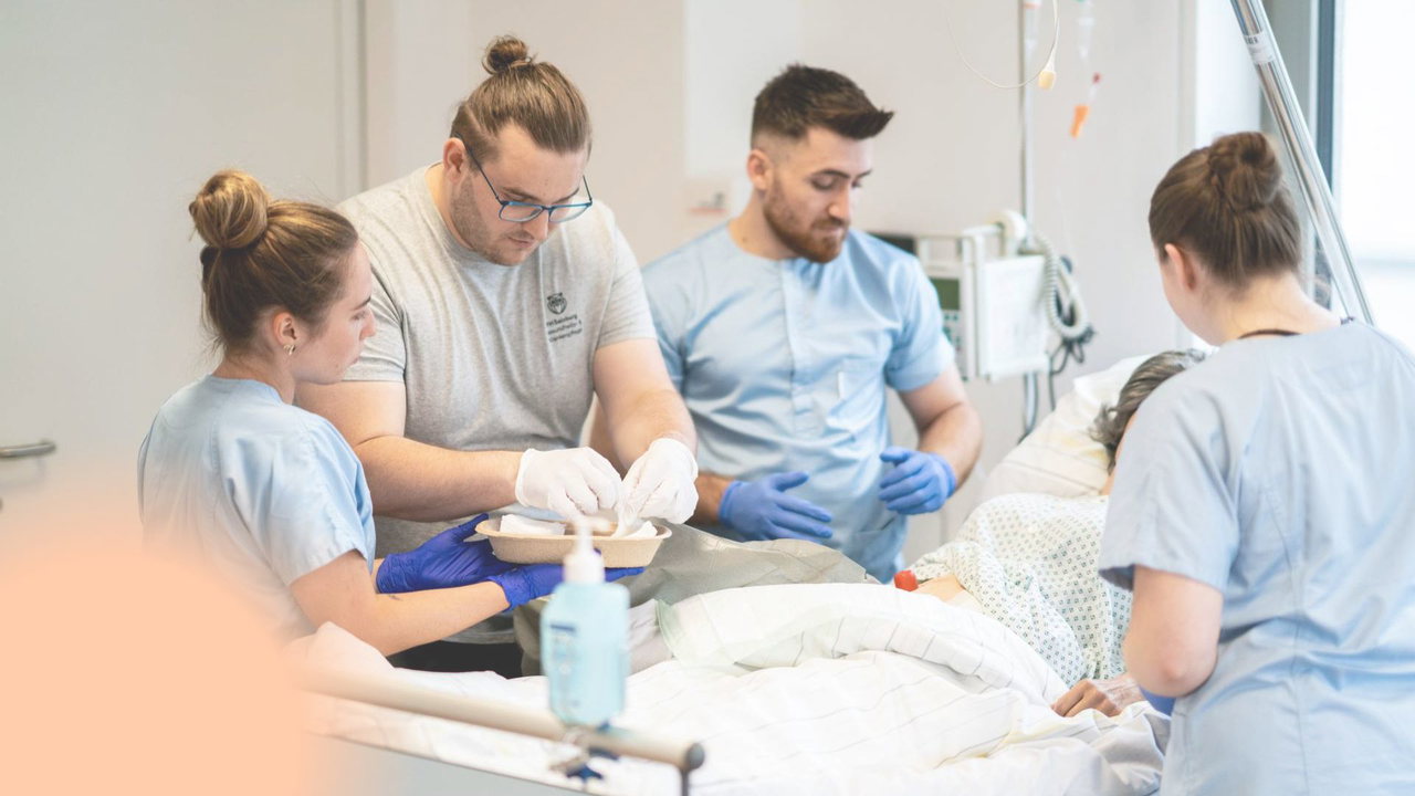 Studierende der Gesundheits- und Krankenpflege üben gemeinsam am Patientenbett