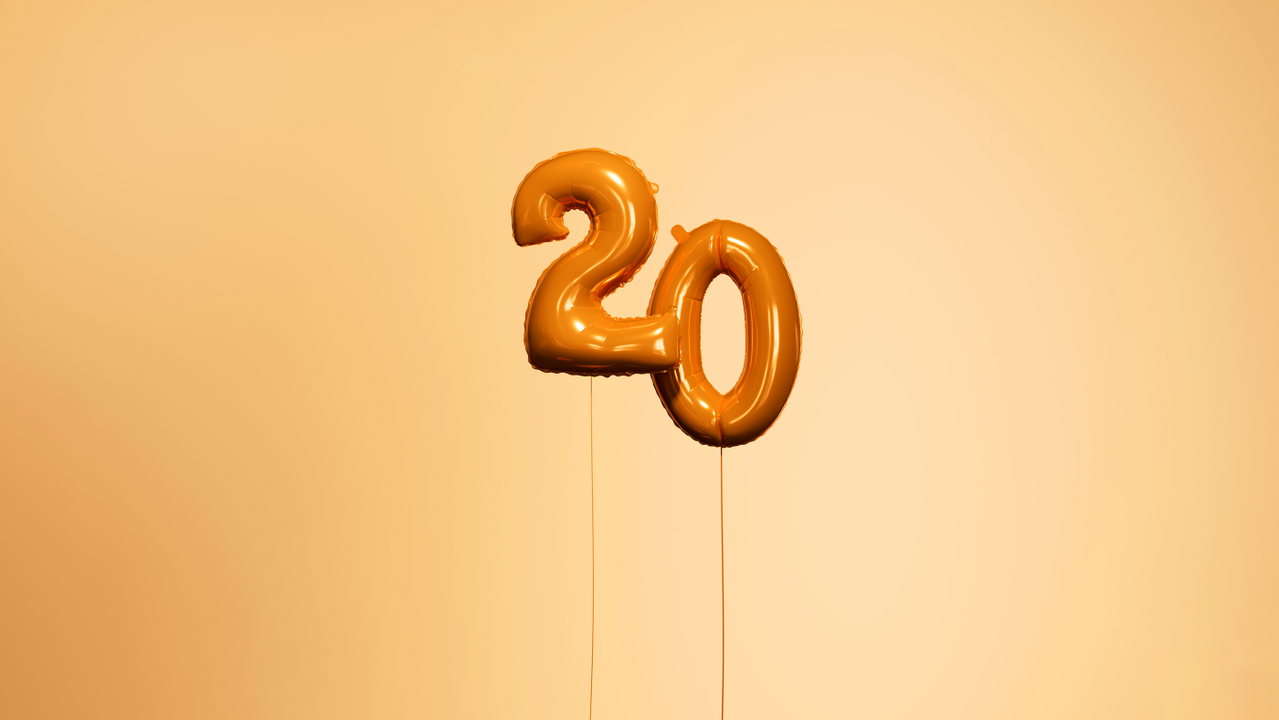 Orangefarbener Folienballon in Form der Zahl 20 vor warmem Hintergrund
