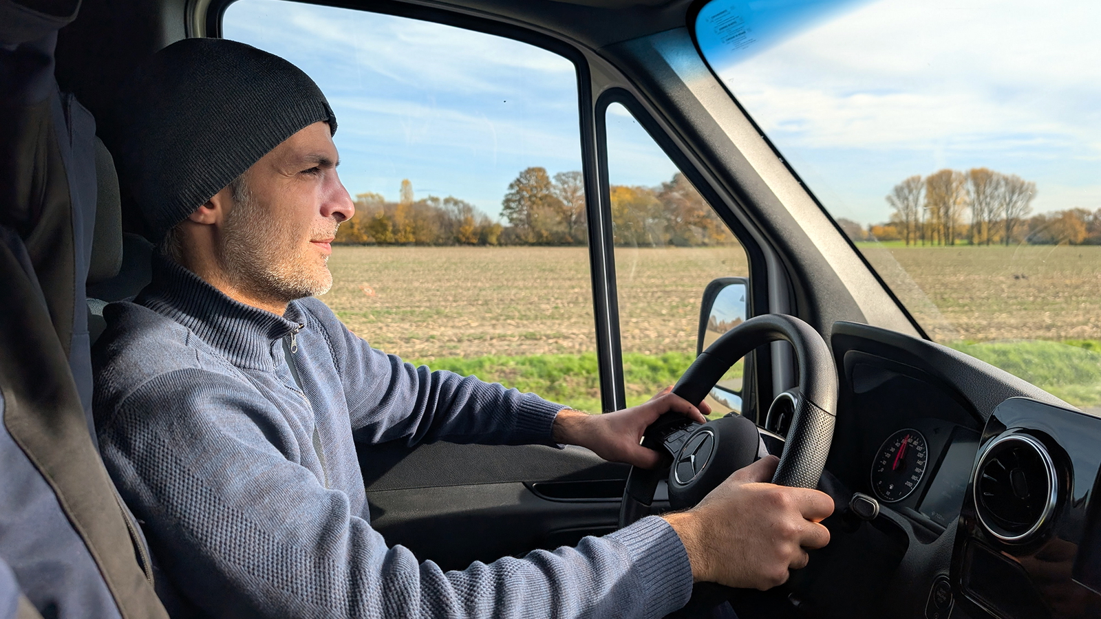 Schwarzer Rubetrans-LKW lädt an einer Ladestation vor einem grauen Gebäude.
