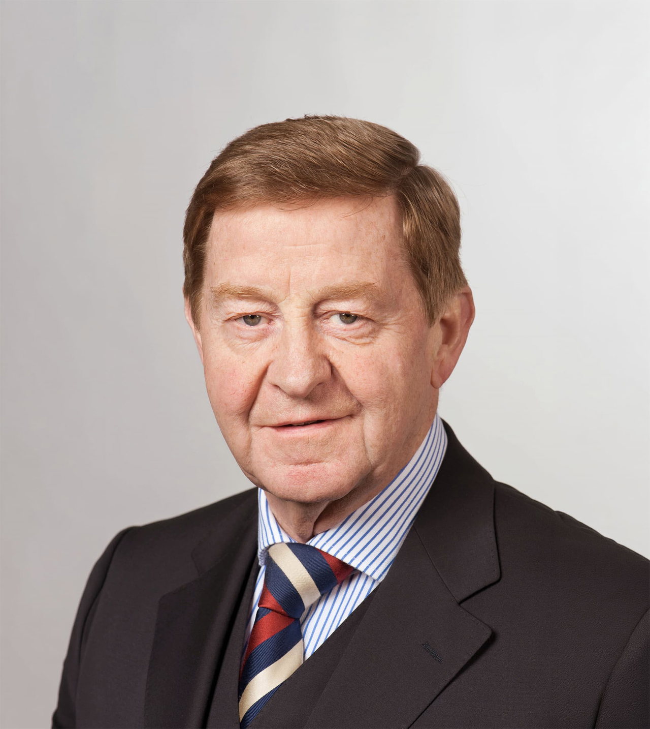Porträt von Doktor Otto Wiesheu vor hellem Hintergrund. Er trägt einen Anzug mit gestreiftem Hemd und gestreifter Krawatte.