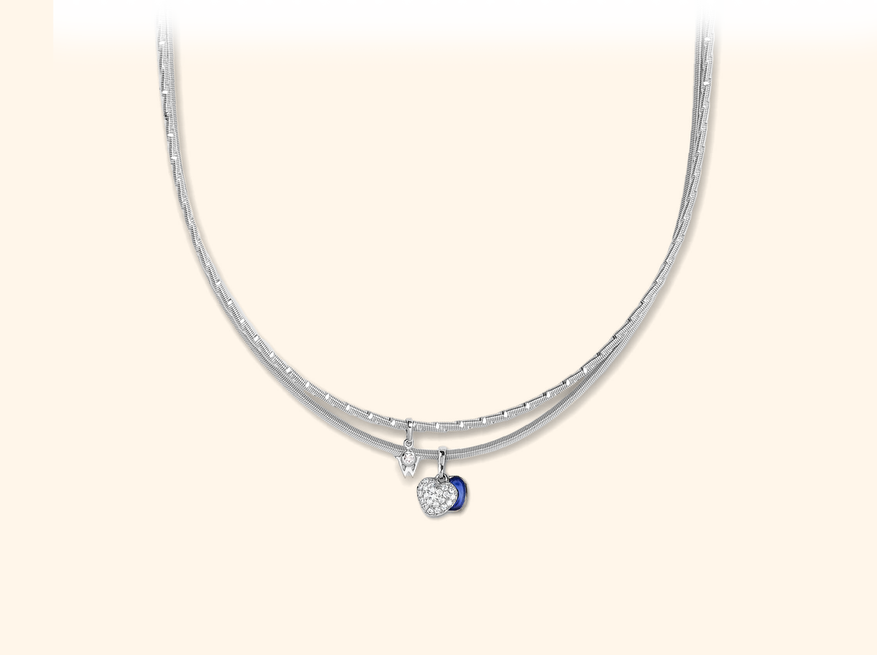 Ein zweireihiges Wellendorff Collier ZWEIKLANG VARIETÉ in Weißgold mit zwei kleinen Anhängern, darunter ein Herz mit Diamanten.