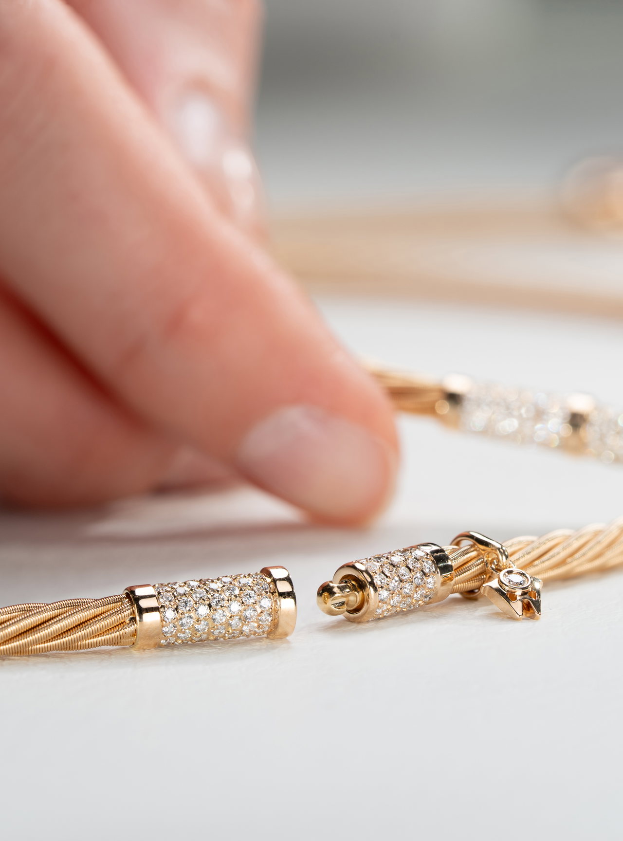 Nahaufnahme der geöffneten Drehkomfortschließe an einem Wellendorff-Collier mit Besatz aus kleinen Edelsteinen und einem kleinen goldenen Wellendorff-W-Anhänger.