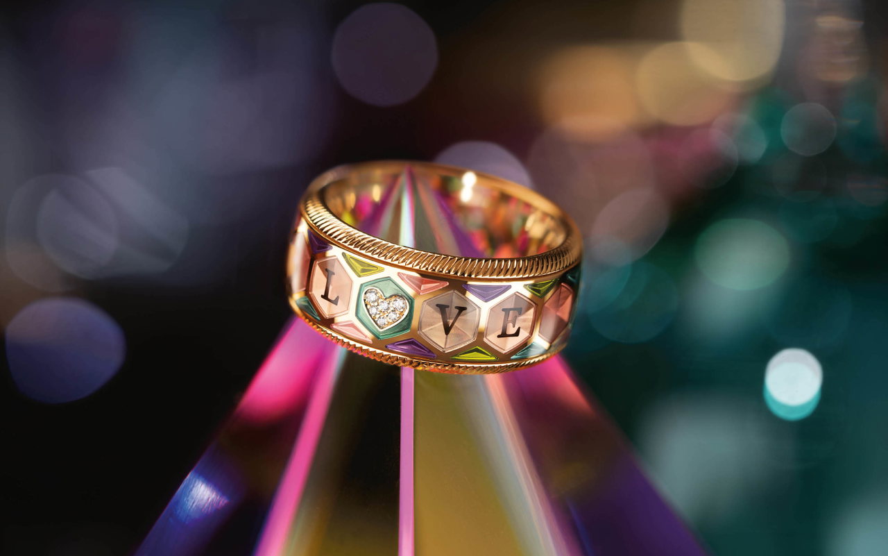 Detailansicht des Wellendorff Jahresrings 2026 AUS LIEBE mit bunten Feldern, dem Schriftzug „LOVE“ und einem Diamantherz vor unscharfem Hintergrund.