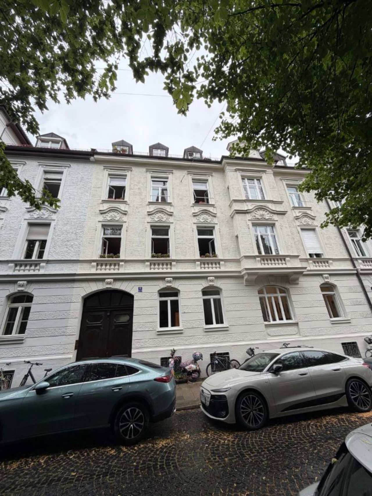 Altbau mit heller Stuckfassade in einer baumgesäumten Straße