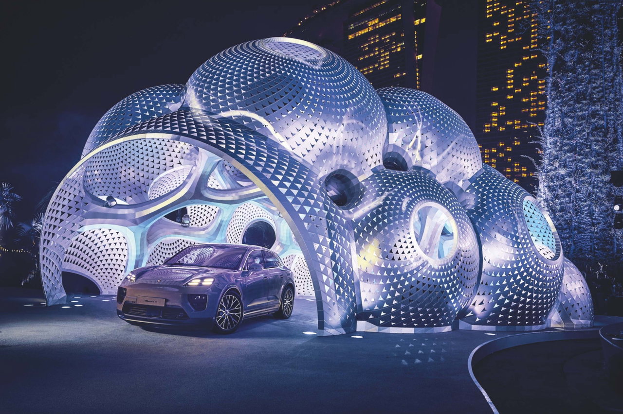 Porsche unter einer futuristischen Pavillon-Konstruktion aus beleuchteten Kugeln bei Nacht