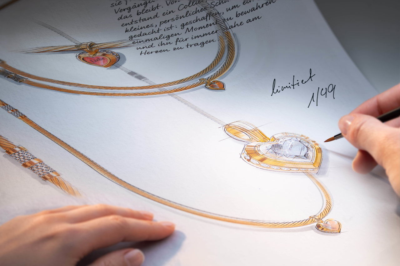 Eine Person zeichnet mit einem Pinsel eine Skizze für ein Wellendorff-Collier mit Herzanhänger.