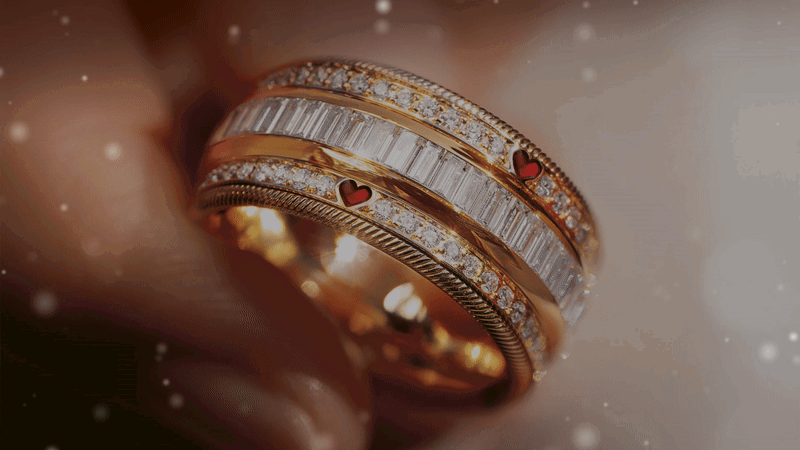Animierte Nahaufnahme des Wellendorff-Rings TWO HEARTS. ONE SOUL, besetzt mit mehreren Reihen von Baguette- und Brillantschliff-Diamanten sowie kleinen roten Herz-Akzenten