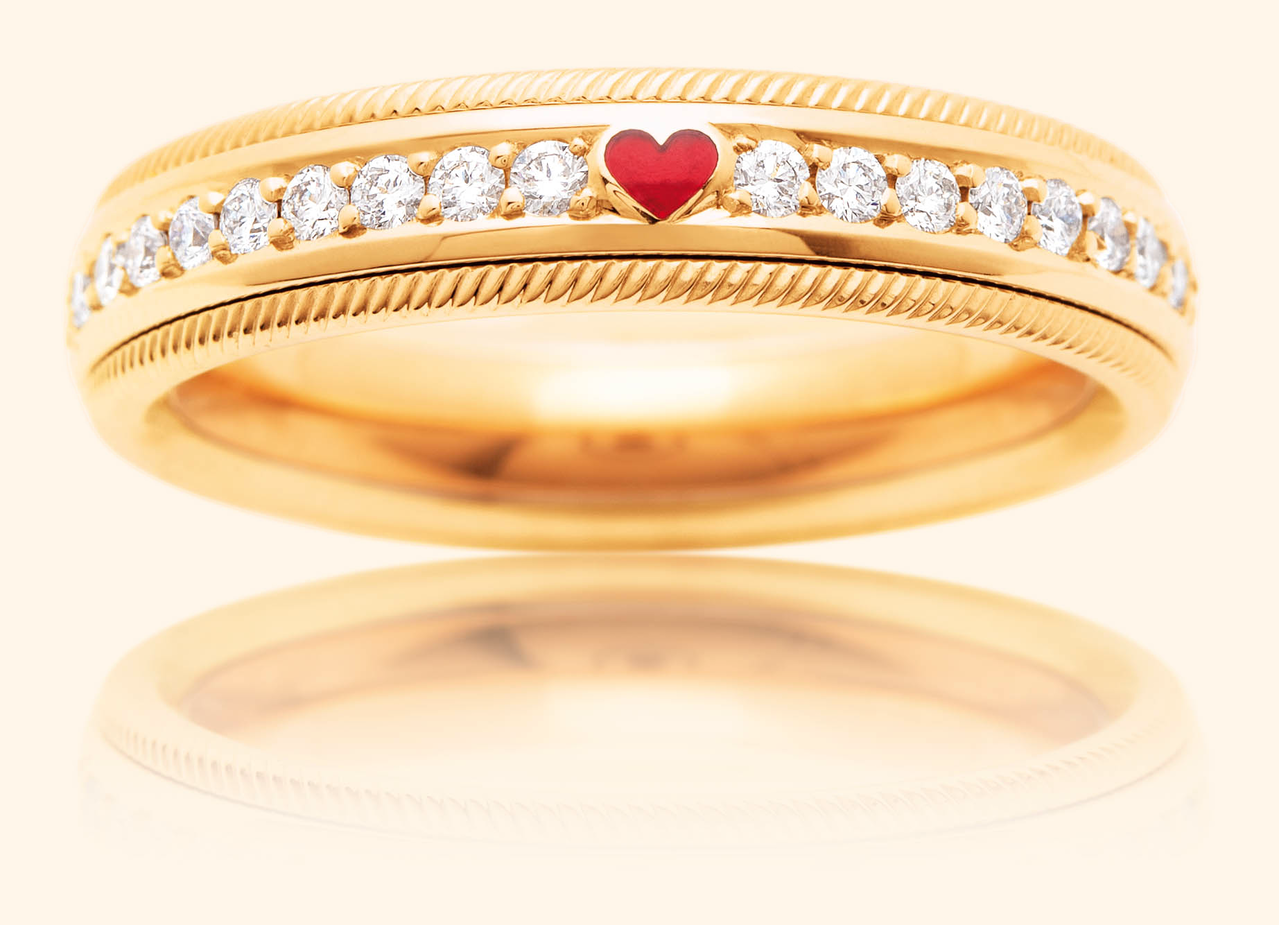 Ein schmaler goldener Wellendorff Ring LIEBESERKLÄRUNG. besetzt mit einer Reihe kleiner Diamanten und einem zentralen roten Herz.