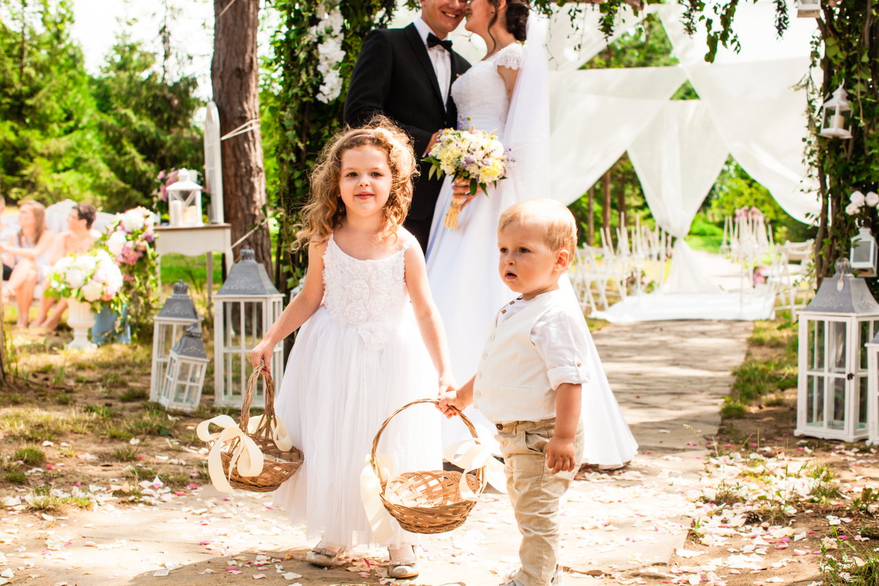 bride-groom-are-smiling-after-wedding-ceremony-adorable-children-with-flying-rose-petals-baskets