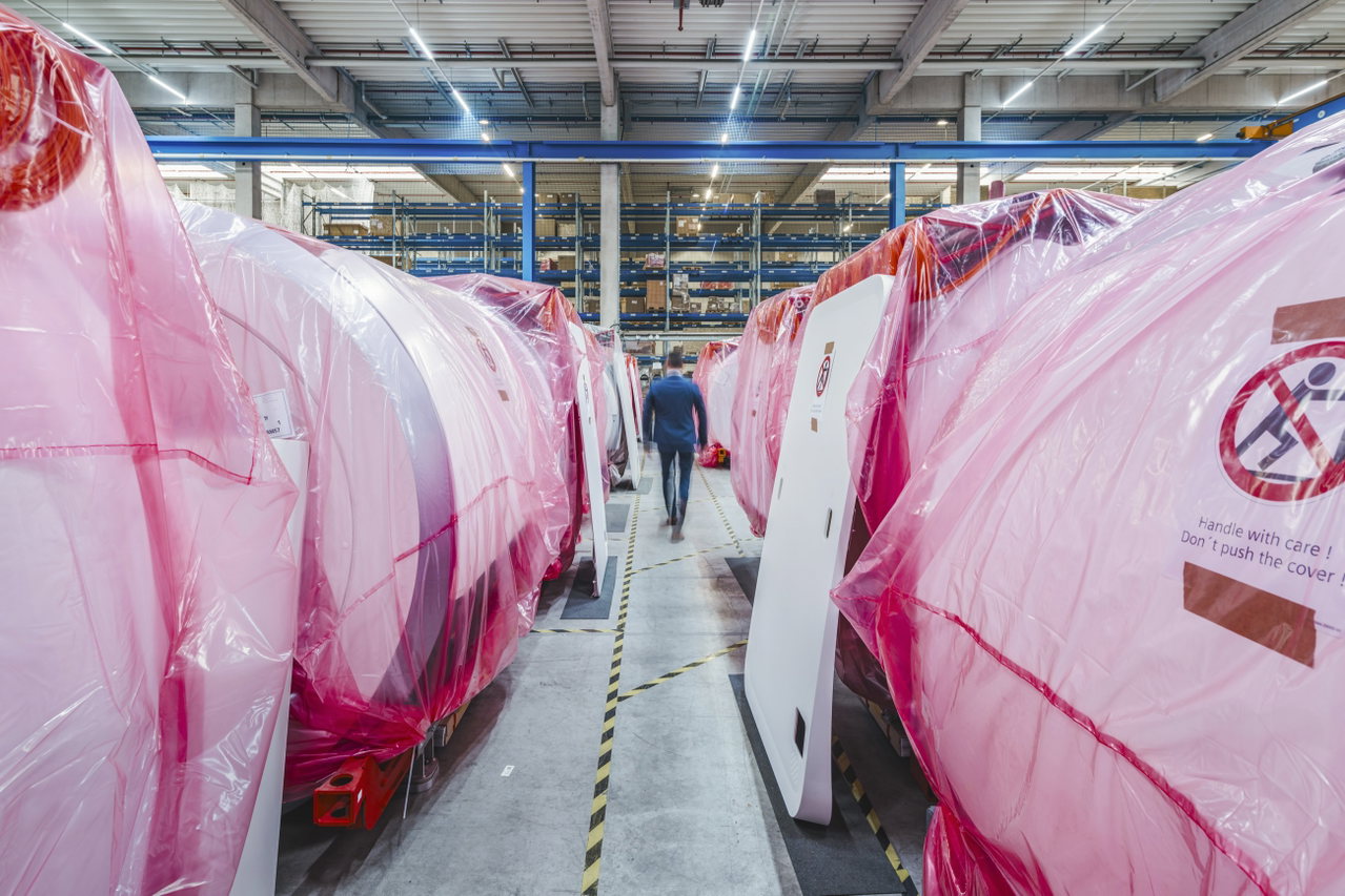 Blick durch eine Gasse zwischen rosa verpackten MRT-Systemen im Lager Frauenaurach