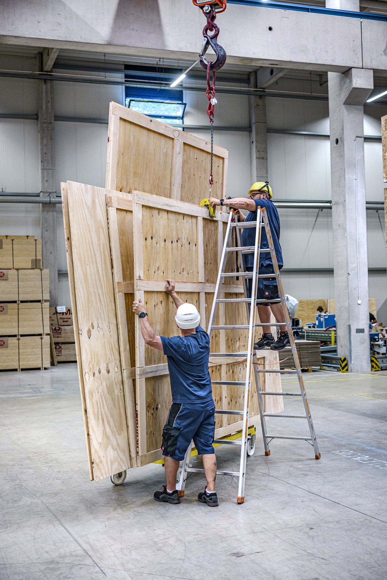 Zwei Mitarbeiter bauen in der hauseigenen Schreinerei eine große Holzkiste