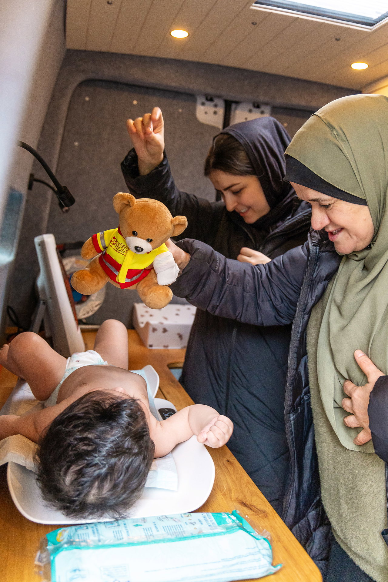 Das Wiegen wird zum kleinen Spiel: Hebamme Nadia Hassan (rechts) nimmt sich Zeit, spricht mit dem Baby von Setara Jubalkhil und greift zum Teddybären.