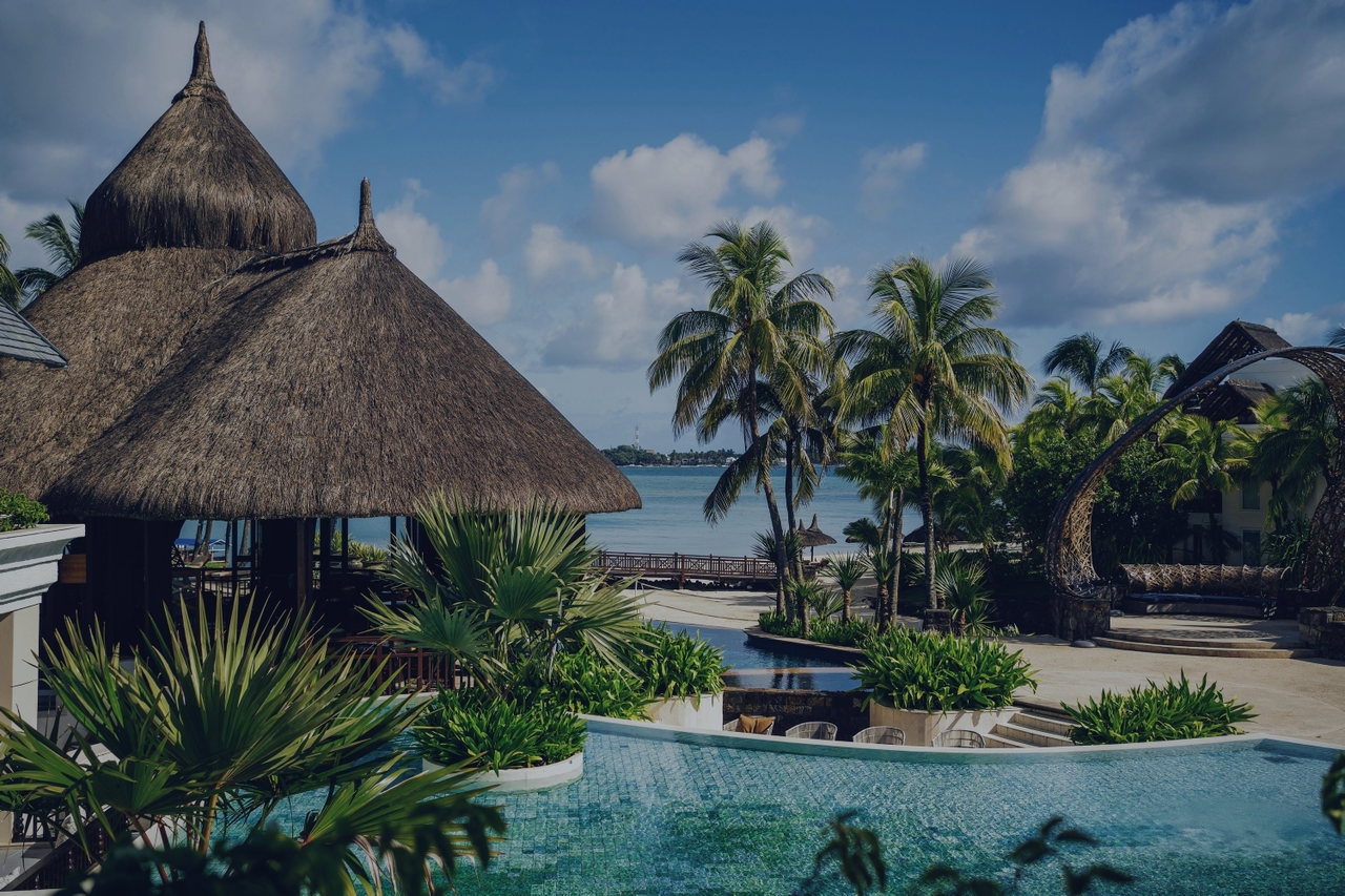 Strohgedeckte Bungalows zwischen Palmen am Meer