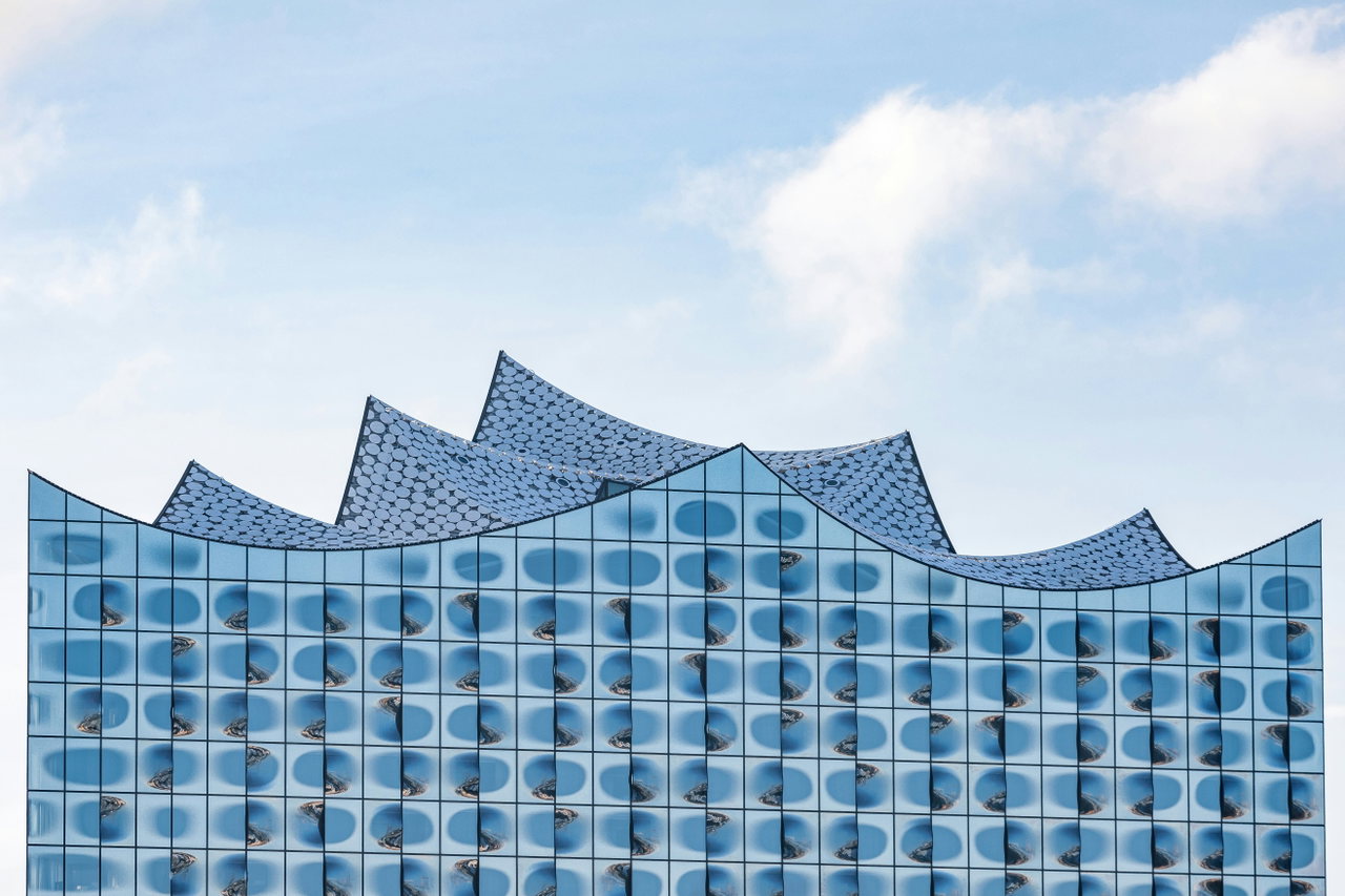 Die geschwungene Dachlinie der Elbphilharmonie vor blauem Himmel