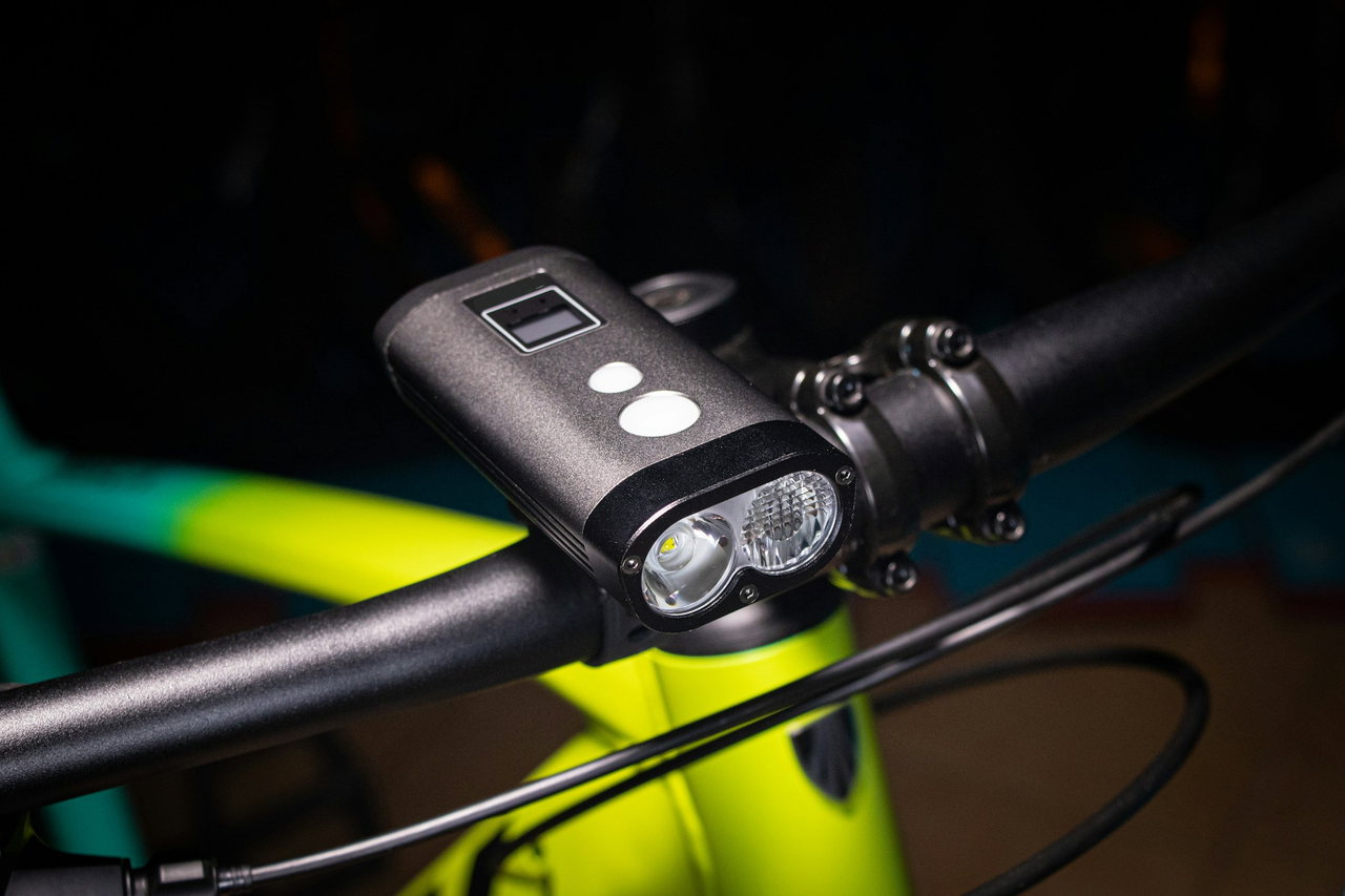 Moderne LED-Fahrradlampe mit kleinem Display am Lenker eines limettengrünen Rads vor dunklem Hintergrund