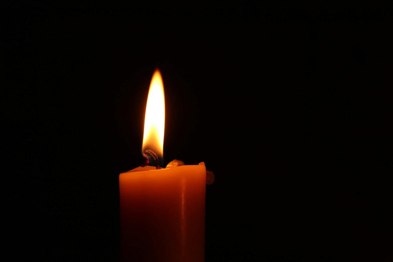 Eine brennende Kerze im Dunkeln, die Flamme warm leuchtend