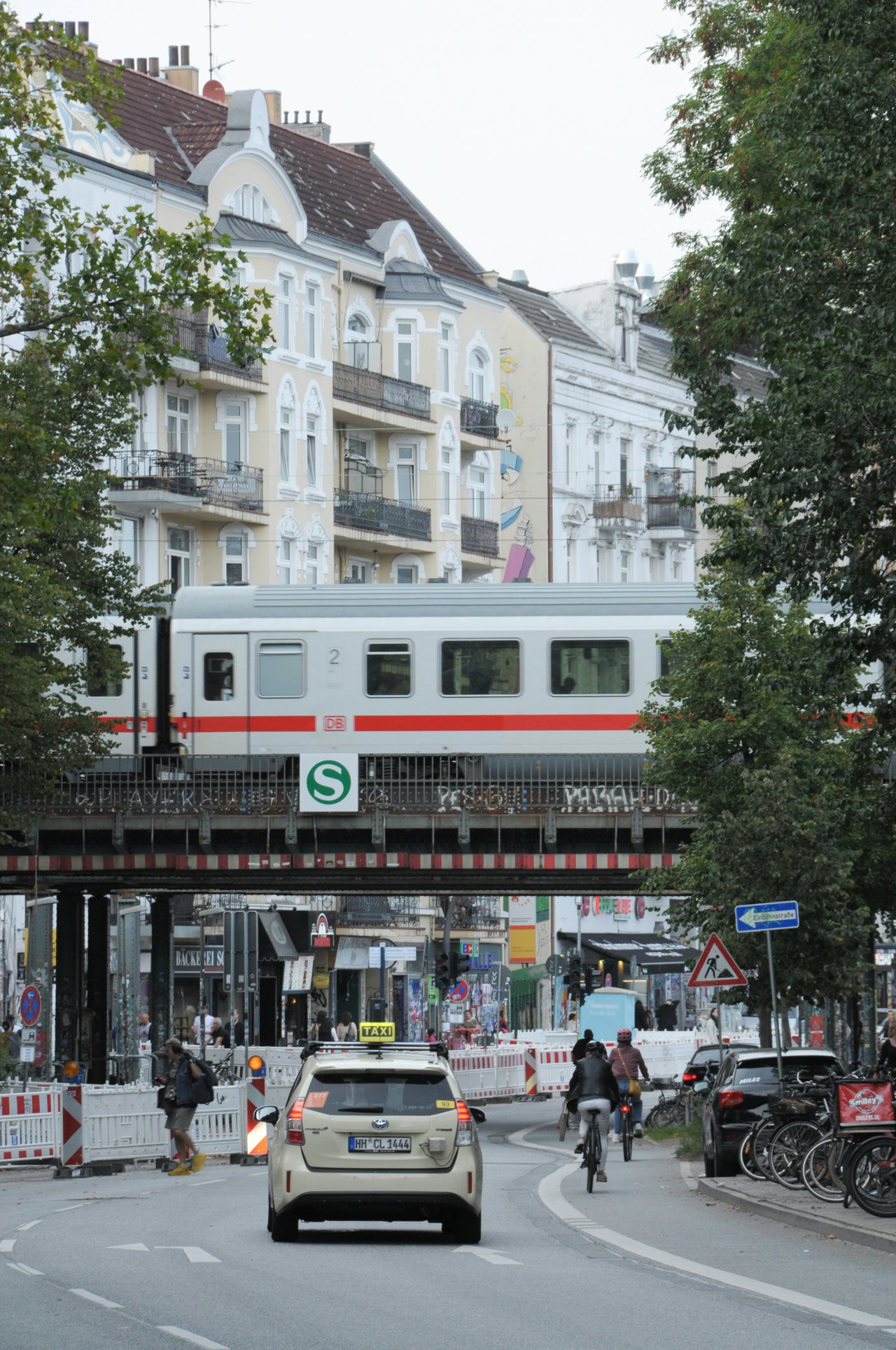 Straße in der Sternschanze, darüber fährt eine S-Bahn über die Brücke