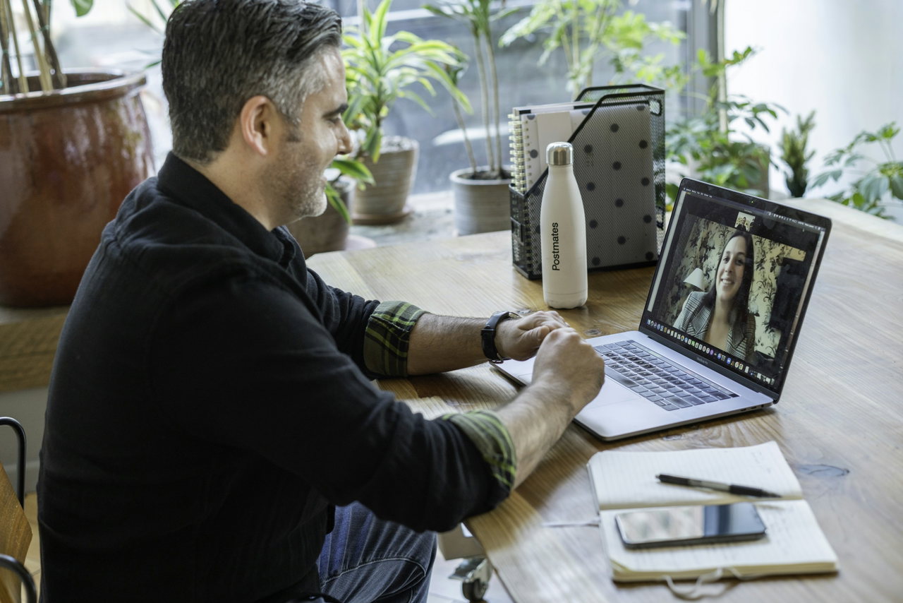 Mann nimmt an einem Online-Seminar teil und schaut auf den Laptop, auf dem eine Gesprächspartnerin zu sehen ist