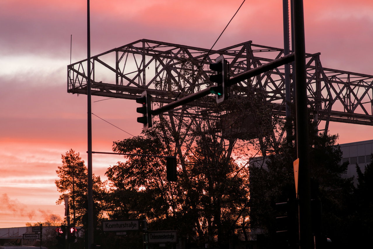 Signalbrücke und Oberleitungen als Silhouette vor pinkem Morgenhimmel