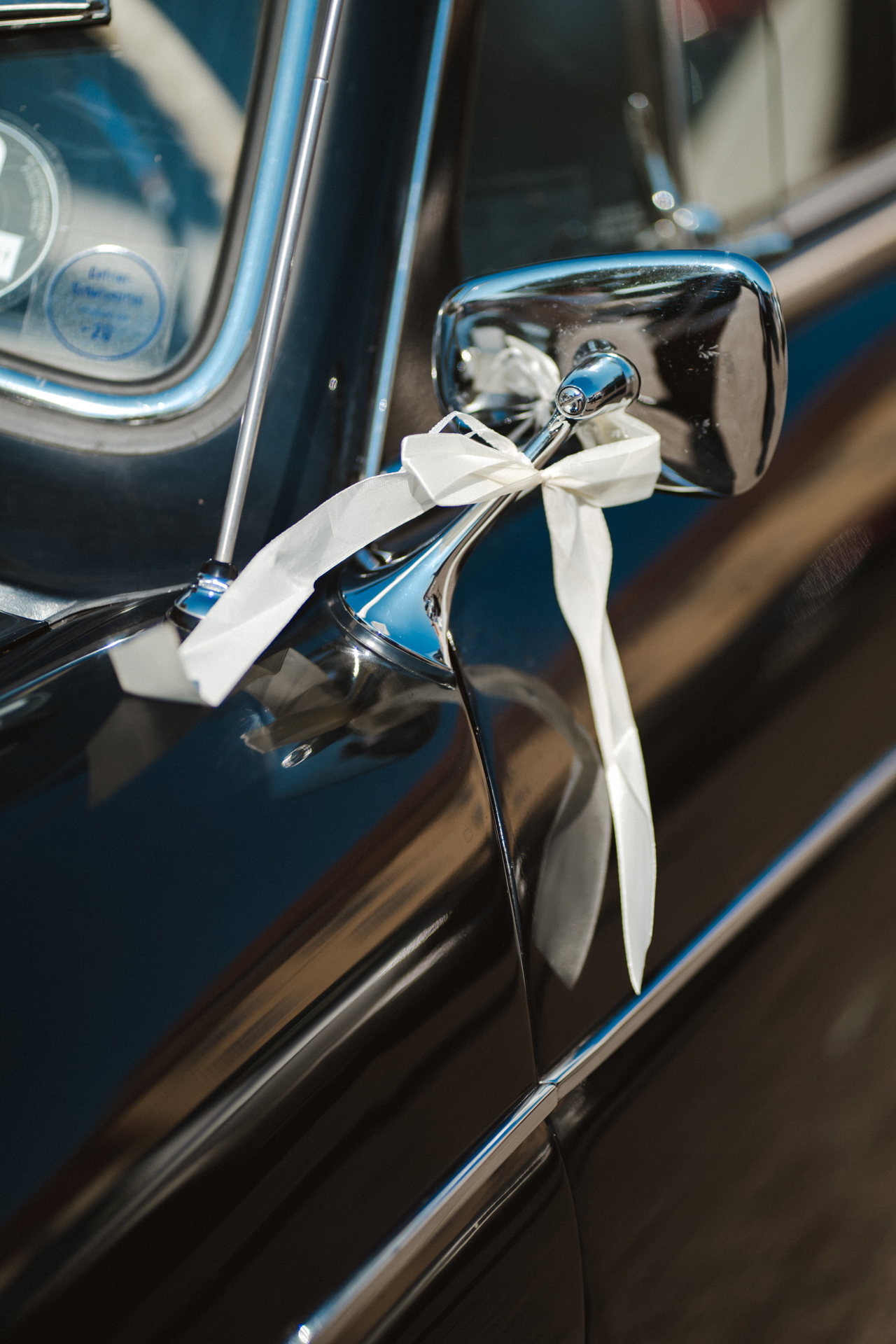 Weiße Satinschleife am Türgriff des Oldtimers
